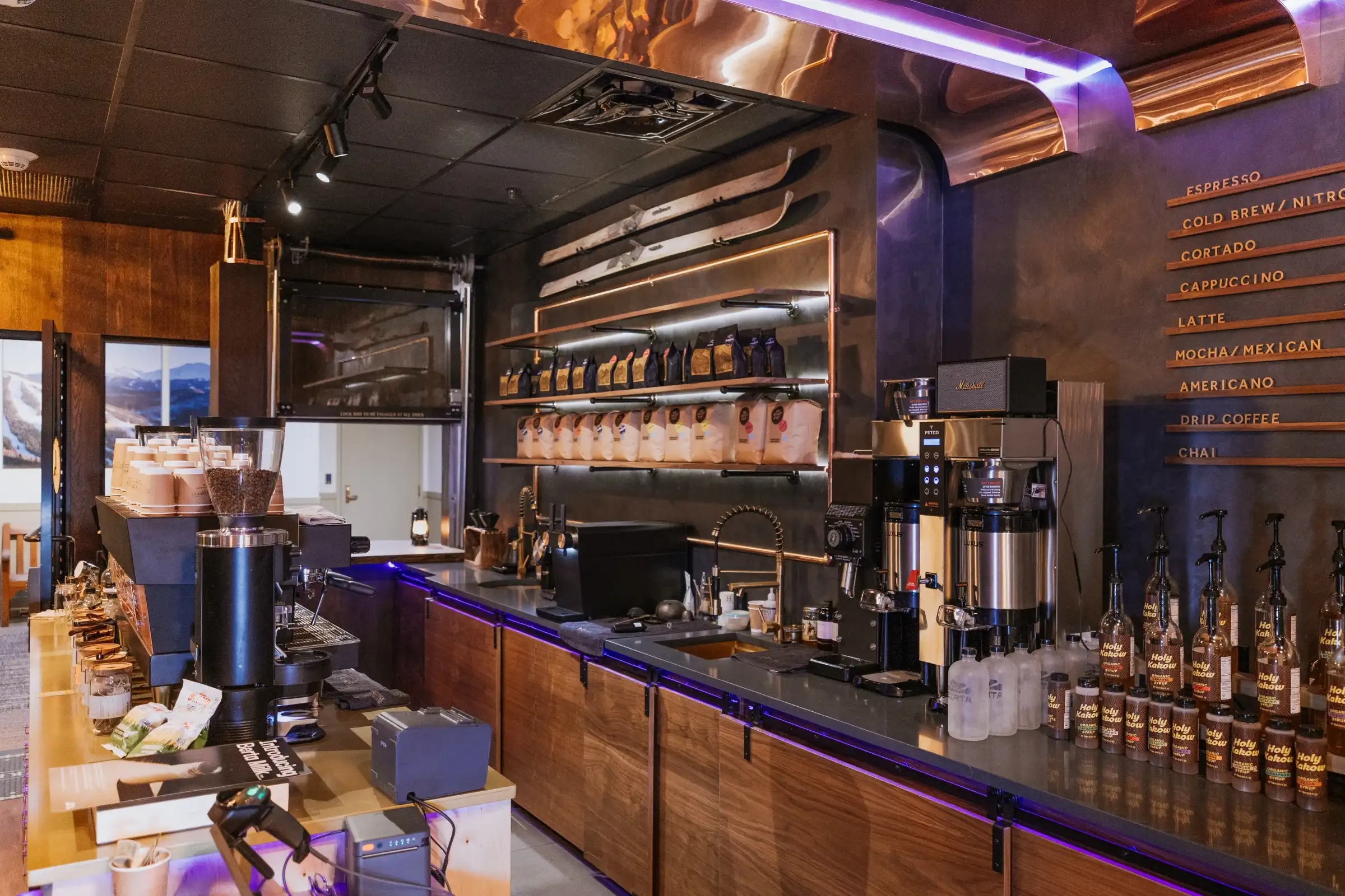 Our bar at Ski Town Coffee: copper shelves of coffee, old skis on the wall and the drink list on a dark wall.