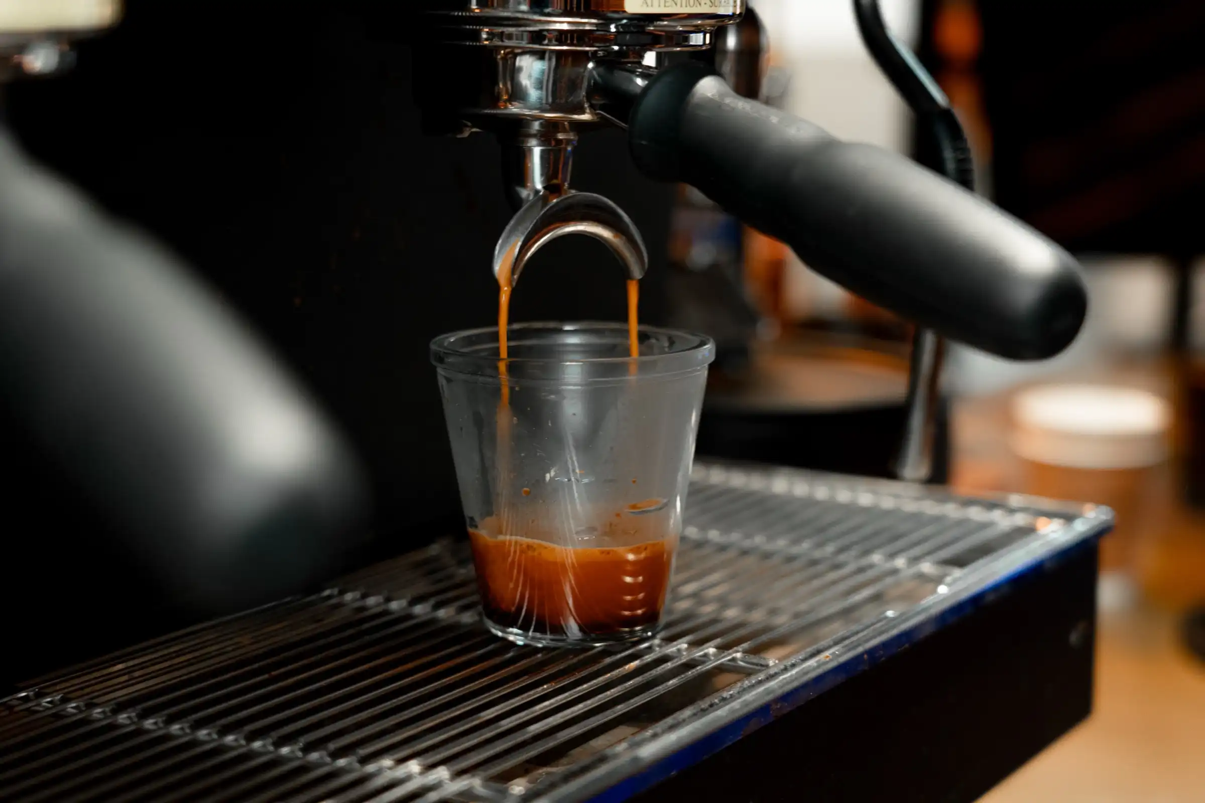 Espresso pouring into a small glass under the group head of our espresso machine.