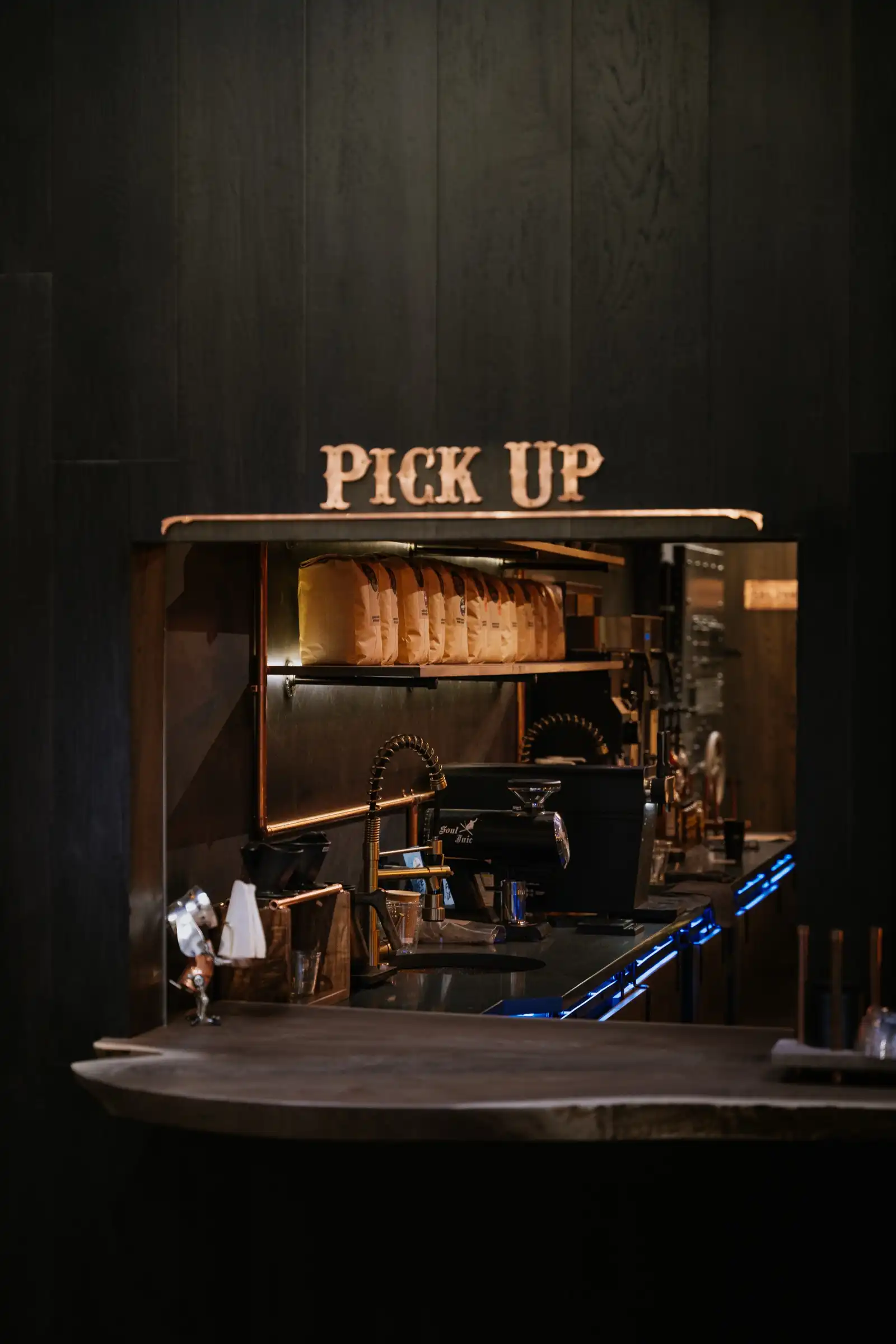 The pick-up window beside our front door, lit from inside, with a copper Pick Up sign above it.