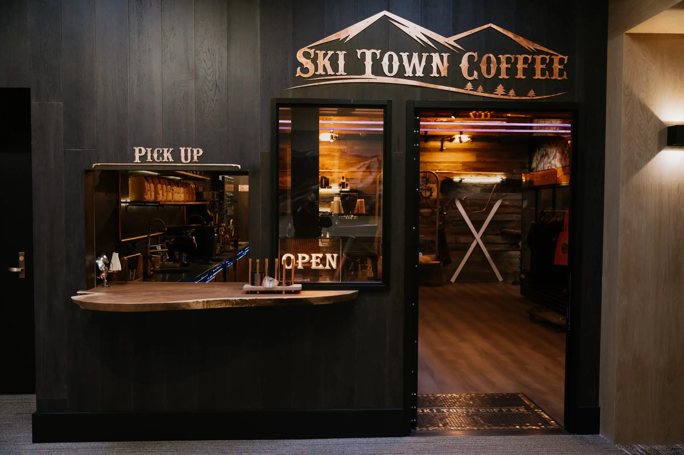 The Ski Town Coffee storefront: black wood walls, the copper Ski Town Coffee sign above the door, a pick-up window and a lit OPEN sign.